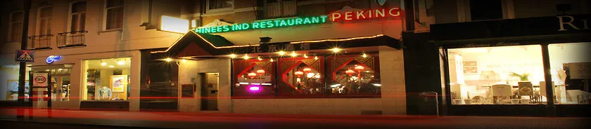 De gevel van Restaurant Peking 's avonds, met de verlichte luifel en lampionnen